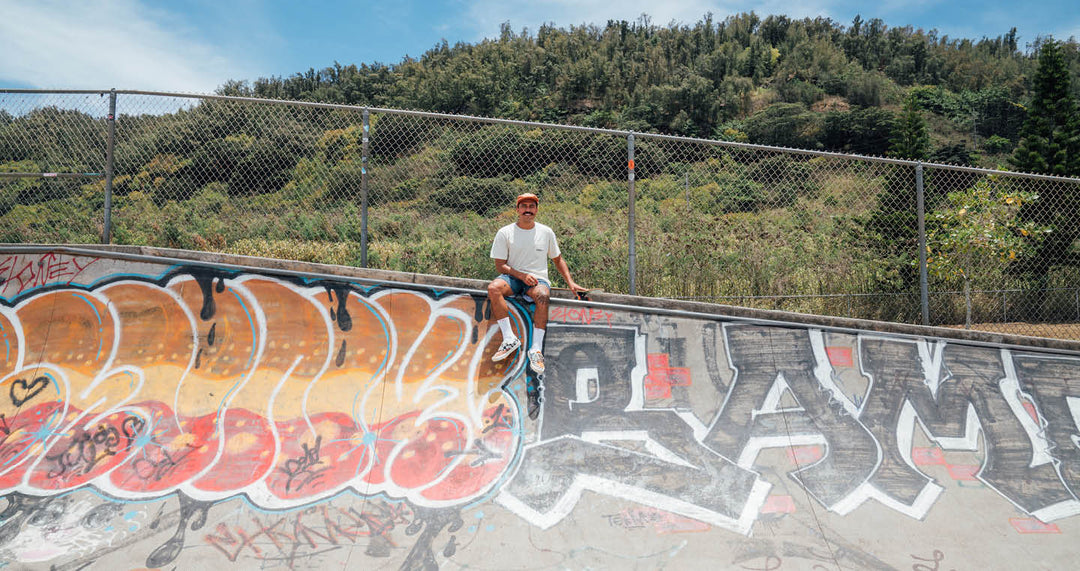 Jack Soren sitting on edge of skate ramp with board by his side