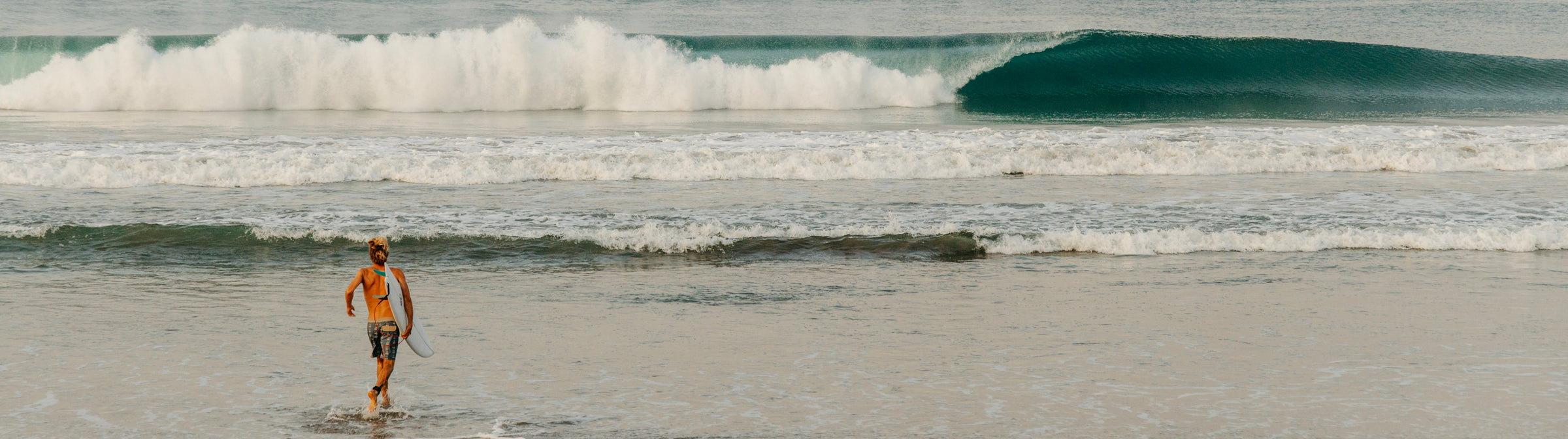 Surfers Andrew Jacobson and Derrick Disney in Vissla Sumer Apparel, holding surfboards and walking through a tropical forest looking for waves