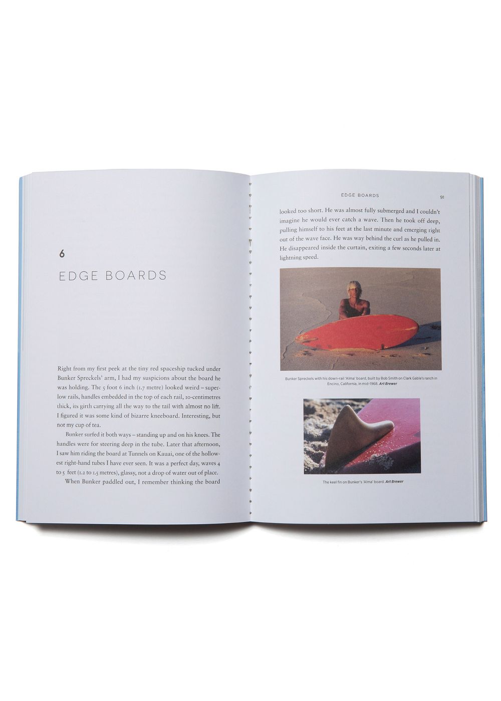 An open book with white pages including black lettering and two images of surfboards